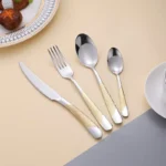 Elegant gold flatware set with steak knife, fork, and spoon on a dark table