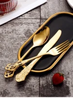 Gold flatware set with spoon, fork, and steak knife on a white tablecloth
