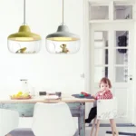 Clear glass LED pendant light with visible filament, suspended in a modern bedroom with neutral decor