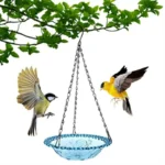Hanging bird feeder bath with a blue bowl and a bird perched on the rim, sipping water.