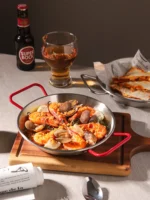 Stainless steel paella pan with double ears on a stove