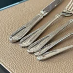 Elegant stainless steel flatware set with mirror finish arranged on a wooden table