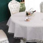 Round linen tablecloth with tassels on a dining table