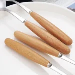 Stainless steel flatware set with wooden handles displayed on a table