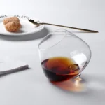 Rotating whiskey glass on a wooden table with amber liquid swirling inside