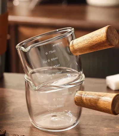 Clear espresso shot glass with handle on wooden surface