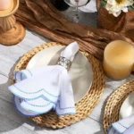 Set of scalloped embroidered napkins in natural color on a wooden table