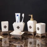 Close-up of the metallic ceramic toothbrush holder, showing its reflective gold surface and rounded shape.