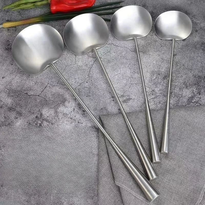 Polished stainless steel soup spoon with long handle on a wooden table