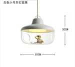Glass house pendant light with exposed bulb, centered in a cozy reading nook with bookshelf