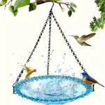 Hanging bird bath in a sunny garden, with the blue bowl casting a shadow on grass.