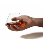 Rotating whiskey glass on a wooden table with amber liquid swirling inside