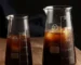 Conical glass coffee pot with hand-brewed coffee dripping into the pot, showcasing its sleek design and measuring marks