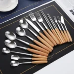 Stainless steel flatware set with wooden handles displayed on a table