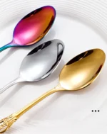 Gold flatware set with spoon, fork, and steak knife on a white tablecloth