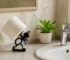 White 3D printed ant toilet paper holder on a bathroom vanity with marble countertop and a small plant.