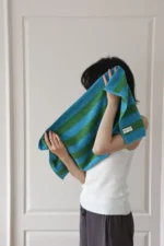 Woman relaxing on a retro striped beach towel for women by Goldoma