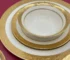 Luxurious gold rimmed dinner plates with intricate relief design on a dining table