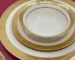 Luxurious gold rimmed dinner plates with intricate relief design on a dining table