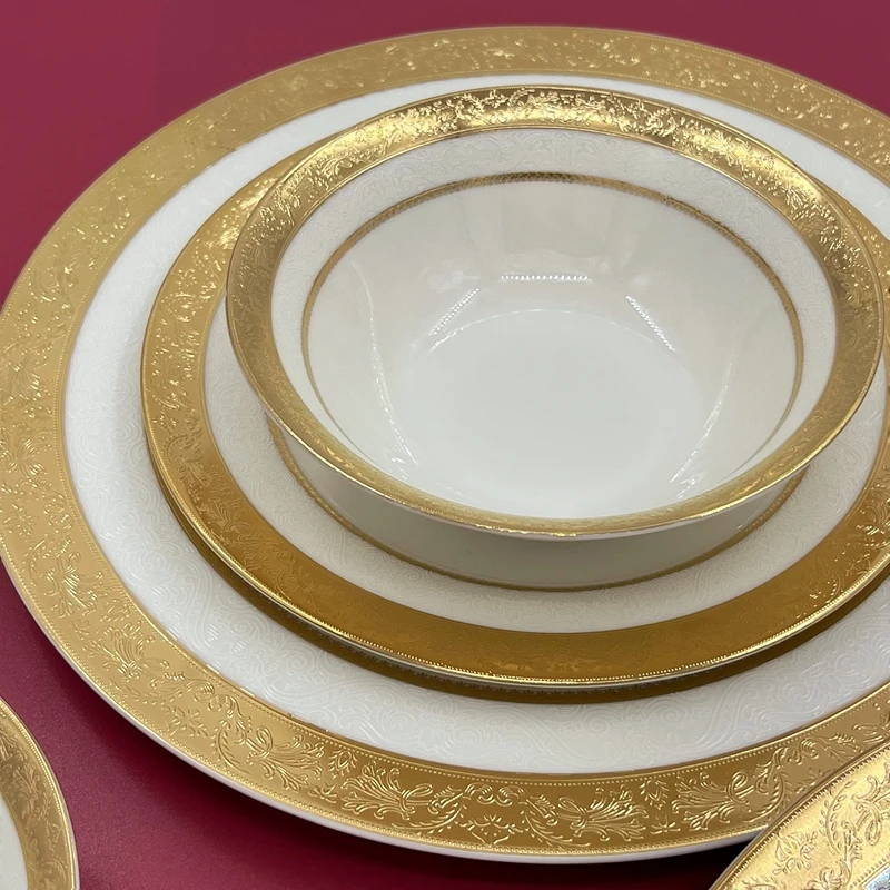 Luxurious gold rimmed dinner plates with intricate relief design on a dining table