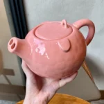Funny pig teapot pouring tea from its snout on a kitchen counter