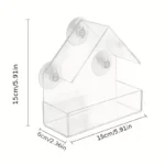 Transparent window bird feeder attached to glass with suction cups, filled with seeds, attracting a cardinal