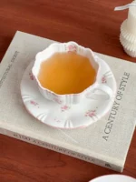 Pink cherry blossom mug with saucer on a dining table
