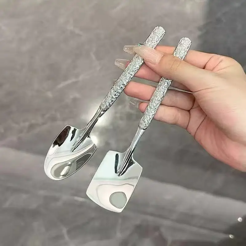 S8aa71f0bbd50457c9d305bb5df2e7e46Y.webp Two stainless steel ice cream spoons with ergonomic handles, one scooping a bowl of vanilla ice cream