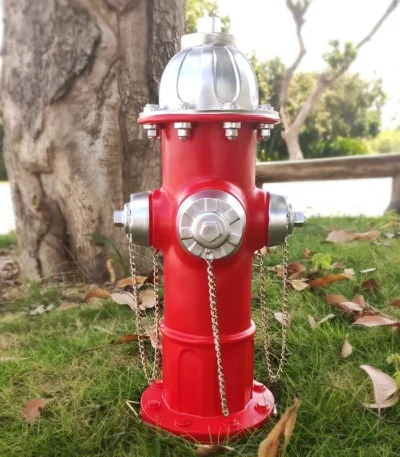 Red fire hydrant garden statue placed on green grass in a sunny backyard