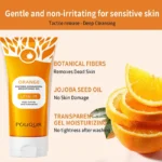 Orange exfoliating cream pump bottle next to a folded white towel on a wooden shelf.