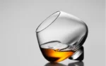 Rotating whiskey glass on a wooden table with amber liquid swirling inside