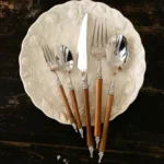 Elegant stainless steel dinnerware set with wooden handles on a rustic table