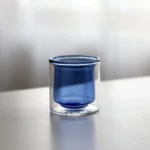 Clear double wall insulated glass mug with espresso coffee on wooden table