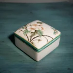 Floral ceramic mouthwash cup, matching toothbrush holder, on marble countertop.
