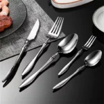Elegant French stainless steel cutlery set with pointed tail handles on a wooden table