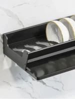 Stainless steel wall mounted dish rack holding plates and bowls in a modern kitchen