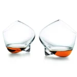 Rotating whiskey glass on a wooden table with amber liquid swirling inside