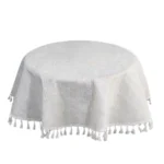 Round linen tablecloth with tassels on a dining table