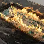 Rectangular propane fire pit table with tile top and wicker base on patio