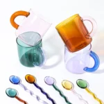 Borosilicate glass mug with coffee and glass spoon on a wooden table