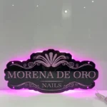 Custom sign with a beauty studio name in cursive, illuminated in warm yellow light.