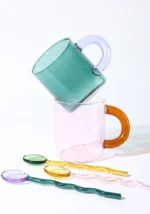Borosilicate glass mug with coffee and glass spoon on a wooden table
