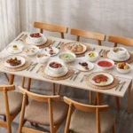 Elegant ceramic plates set with dinner plates, dessert plates, cereal bowls, and soup bowls arranged on a wooden table