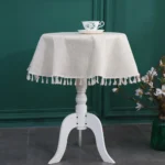 Round linen tablecloth with tassels on a dining table
