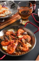 Stainless steel paella pan with double ears on a stove