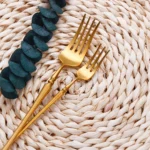 Matte gold flatware set with antique finish arranged on a wooden table