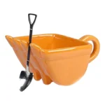 Excavator mug with spoon on a wooden table, ceramic bucket-shaped mug with a metal shovel spoon