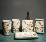 Floral ceramic lotion bottle, pump top, on bathroom counter with toothbrush holder.