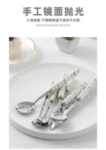 Stainless steel flatware set with ceramic pearl handles on wooden table
