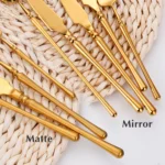 Matte gold flatware set with antique finish arranged on a wooden table